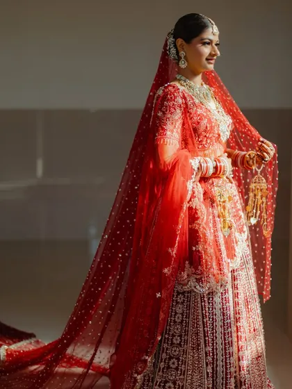 A beautiful shot of the bride getting her final touches. The sheer red dupatta adds a layer of tradition and mystique to her overall look.