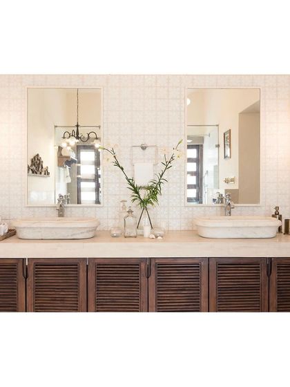 The master bathroom at Loto Bianco, featuring a double vanity with marble sinks and louvered wood cabinets for a classic, tropical feel.