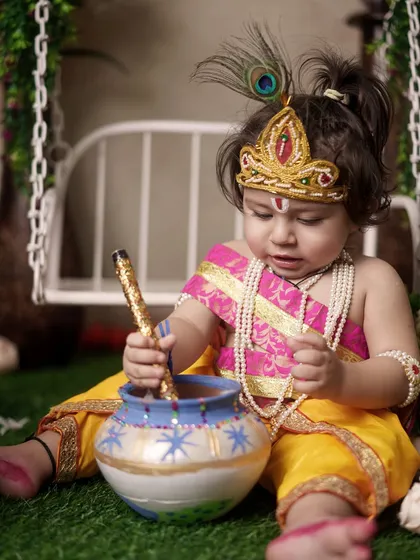 This toddler, dressed as Krishna, is completely absorbed in playing with the prop matki. I let kids interact with the props naturally to capture their authentic curiosity.