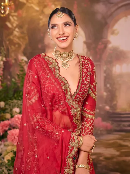A candid moment of laughter. This image captures the bride's happiness, with her elegant red attire and our timeless makeup shining through.