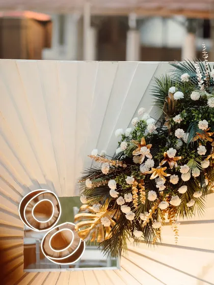 A close-up of the decor for a Roce ceremony. This shot highlights the modern white pleated backdrop, lush floral arrangements with gold accents, and unique circular light fixtures.