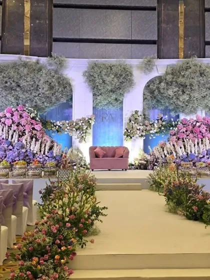 A view from the aisle of the pastel floral stage, showing the guest seating with matching purple bows.