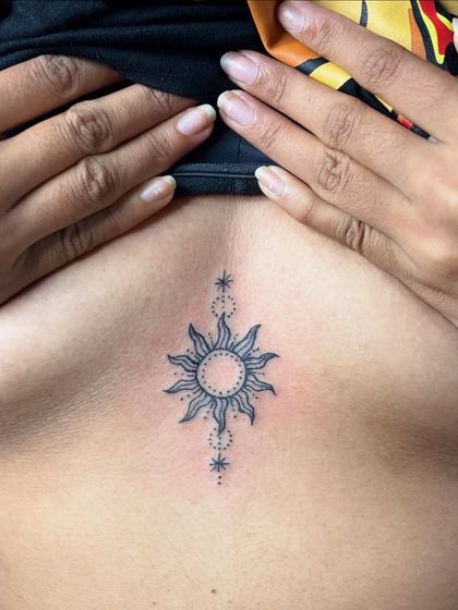A healed photo of the fine-line sun sternum tattoo, looking clean and sharp.