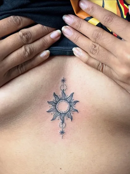 A healed photo of the fine-line sun sternum tattoo, looking clean and sharp.