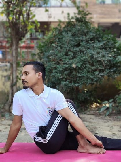 An instructor demonstrates Ardha Matsyendrasana (Half Lord of the Fishes Pose), a seated twist that improves spinal mobility and aids digestion.