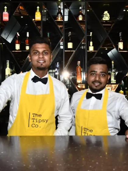 Two of our sharp-dressed bartenders ready for service. Wearing our signature yellow aprons and bow ties, they represent the professionalism and energy of our team.