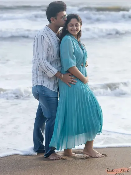 A sweet and intimate pose with the couple standing back-to-back by the ocean. He gently kisses her head, creating a feeling of love and protection in this beautiful outdoor setting.