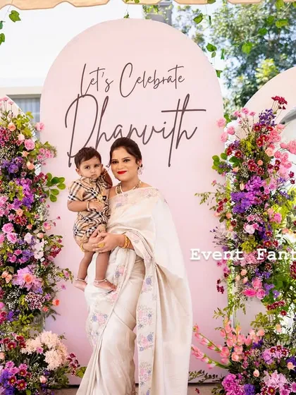 There is nothing more rewarding than seeing a family's joy. Here is the lovely mother and her son Dhanvith, celebrating in front of a custom backdrop of lush, cascading flowers in shades of pink and purple that I designed for their special day.