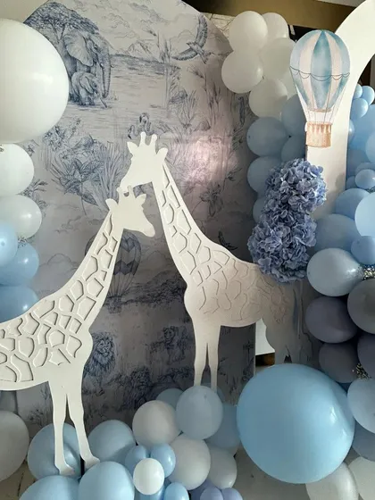A close-up of the Dior-inspired baby arrival setup. The toile-style backdrop and the elegant giraffe cutouts create a high-fashion, chic welcome for the new baby.