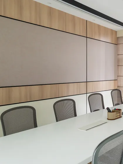 A detail shot of the conference room wall, which combines wood panels with a fabric-finish pinboard for acoustic comfort and functionality. The neutral palette promotes a calm and professional atmosphere.