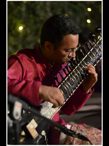 A close-up showing the intricate fingerwork on the sitar's frets.