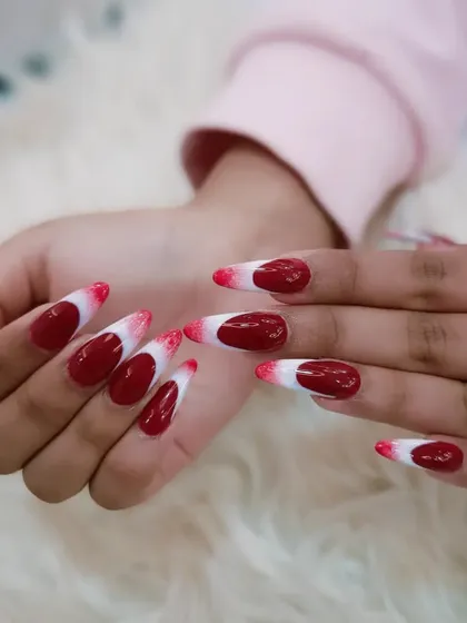 A bold red and white design with a unique gradient effect on almond-shaped nails.