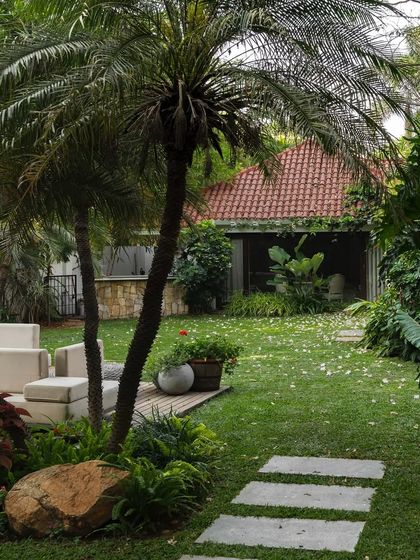 A view of a lush backyard where a stone path cuts through the grass. The design preserves the natural, relaxed feel of the space while providing structure and guiding movement through the garden.