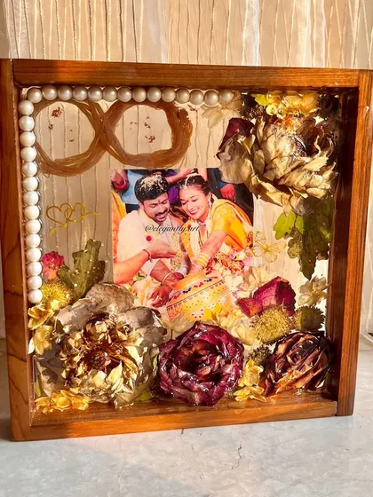 This 10-inch teakwood frame beautifully preserves a couple's wedding garland, with the sacred wedding threads formed into an infinity symbol. It's a custom-made piece that tells a unique love story.