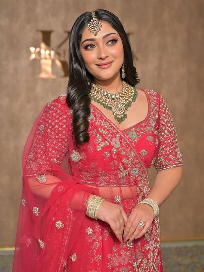 This model wears a beautiful red lehenga with a green-beaded Kundan necklace, demonstrating how we can match jewellery to the accent colors in your outfit.