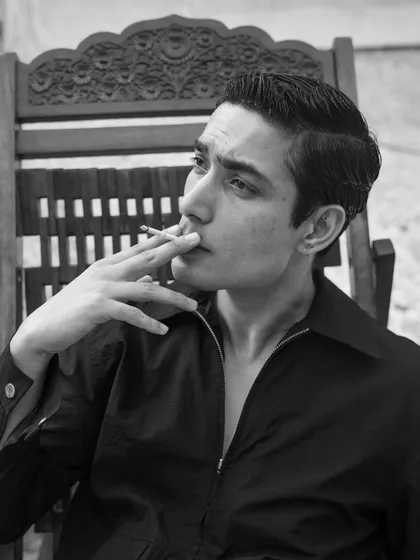 A black and white portrait that feels like a still from a classic film. The model's retro hairstyle and the act of smoking create a nostalgic and effortlessly cool vibe.
