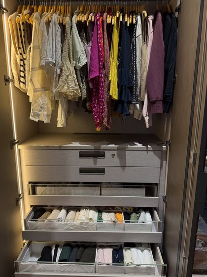 A full view of a wardrobe section with hanging clothes above and multiple pull-out drawers below, demonstrating our approach to maximizing vertical space.