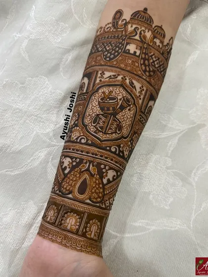 A close-up of a completed armband featuring peacocks, elephants, and a dhol-shehnai motif, showcasing the clean, bold lines.