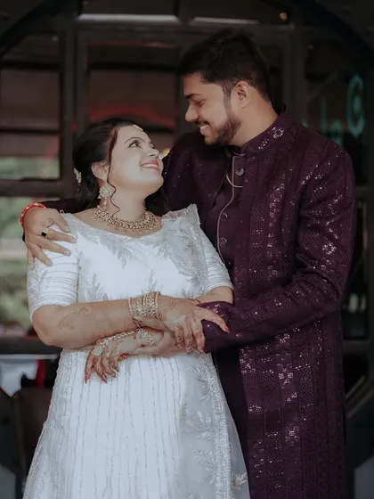 A sweet portrait of an engaged couple sharing a look of love, highlighting their elegant white and purple outfits.