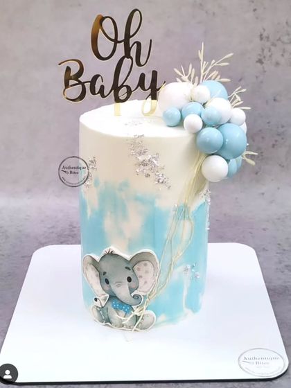 An "Oh Baby" shower cake with a cute baby elephant. The blue watercolor effect and balloon cluster create a modern and charming design.
