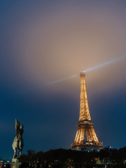 A magical night shot of the Eiffel Tower, its beacon of light cutting through the misty sky. This atmospheric photo captures the enchanting and iconic beauty of Paris after dark.
