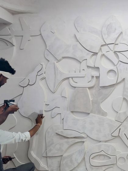 Two artisans are seen applying the final details to the 'cosmic tapestry' plaster mural, demonstrating the hands-on, collaborative nature of our studio.