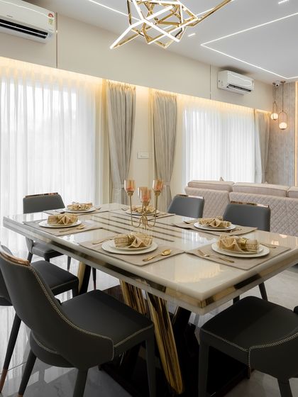 A closer look at a dining setup where design meets decadence. The marble-topped table with gold-finished legs is complemented by a geometric chandelier, creating a sophisticated space for memorable meals.