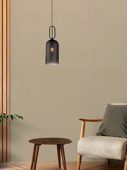 A single mesh cage pendant shown as an accent light in a cozy reading corner. Its industrial-chic design adds texture and character to the minimalist space.