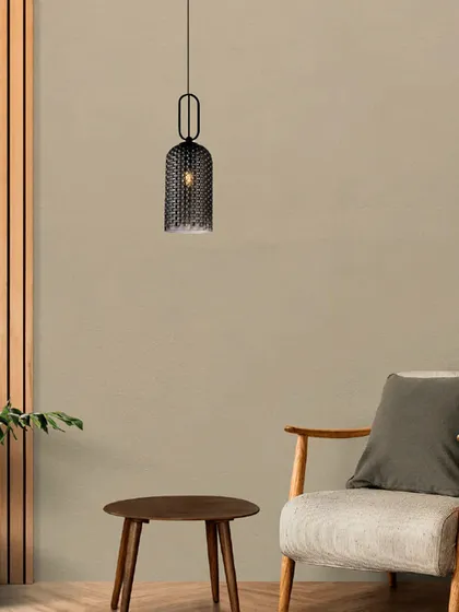 A single mesh cage pendant shown as an accent light in a cozy reading corner. Its industrial-chic design adds texture and character to the minimalist space.