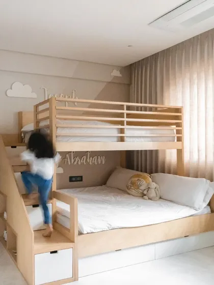 For this children's room, we custom-designed a playful and practical bunk bed with built-in stairs that double as storage. The light wood and personalized names make it a fun and adventurous space for siblings.
