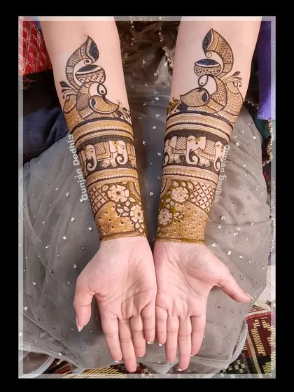 The start of a beautiful bridal mehendi. This design features peacock and elephant bands on the arms, setting the stage for the intricate work on the palms.