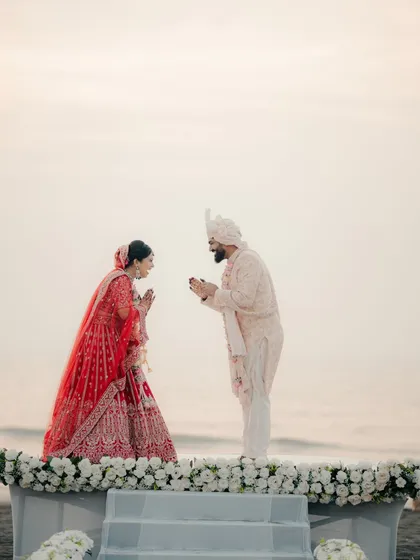 A respectful and traditional greeting on a stage set against the ocean. This image perfectly blends culture with the beauty of a destination wedding.