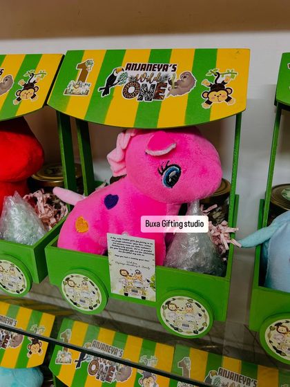 Welcome to the jungle! This "Wild One" birthday hamper comes in a green and yellow cart, filled with a soft toy, coconut cookies, trail mix, and a jungle-themed candle.