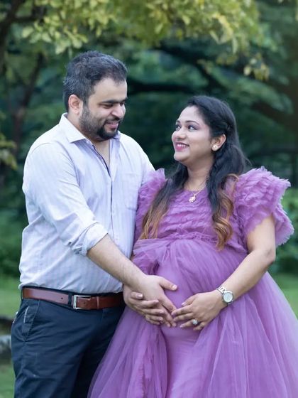 A classic, loving pose with the husband's hands around his wife's baby bump. Their shared look of happiness says everything about the journey they are on together.