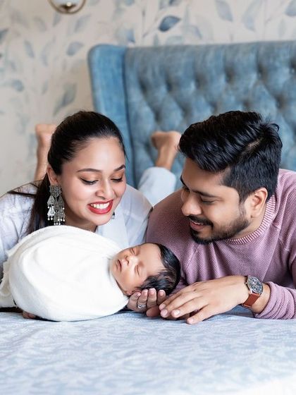 A lifestyle family portrait with a newborn on the bed. The parents' loving gaze says it all.