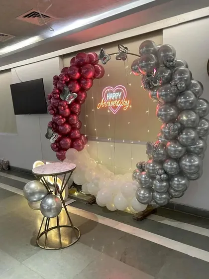 A side view of the anniversary balloon arch, showing the detail of the chrome and magenta balloons and the fairy lights inside the ring.