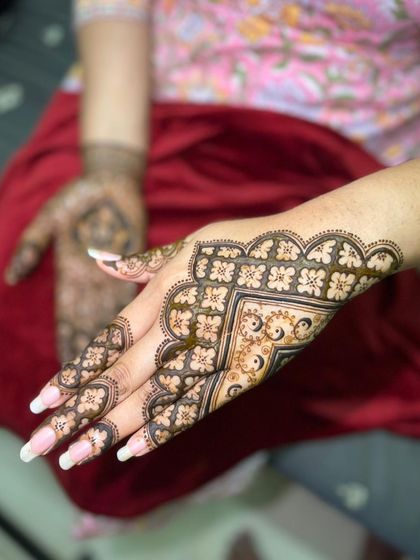 A close-up of a beautiful engagement mehendi, showing the intricate geometric and floral patterns on the back of the hand.