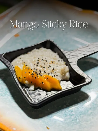 A beautiful serving of my Mango Sticky Rice. This classic Thai dessert features sweet, coconut infused sticky rice paired with fresh, ripe mango slices and a sprinkle of sesame seeds for a perfect end to any meal.