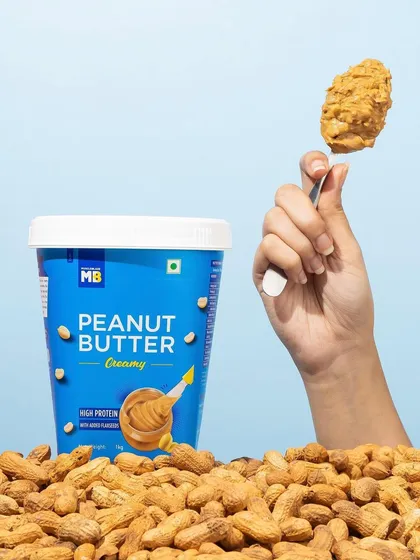 A simple, effective shot that highlights the delicious texture of creamy peanut butter. The hand holding up the spoonful makes the product feel instantly craveable and ready to eat.