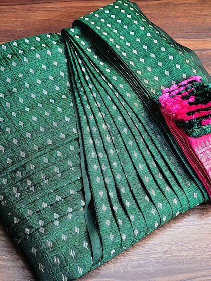 This green and pink silk saree is ready to be delivered to a client. The box fold keeps the entire drape, including the decorative tassels, safe and organized.