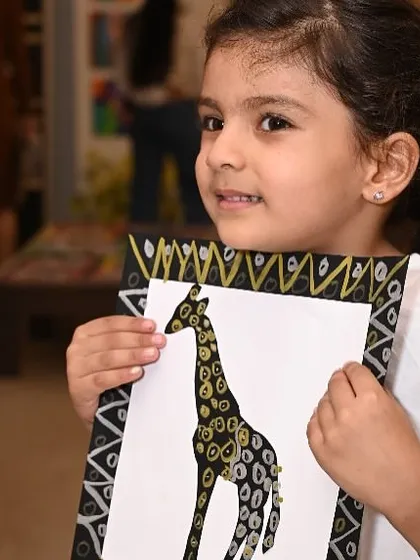 The pure joy and pride on a young artist's face when she completes her work is why I do what I do. This student is holding her beautiful giraffe painting, created during our annual exhibition project.