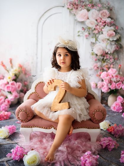 Holding up the number '2' to proudly mark her second birthday in this beautiful floral-themed session.