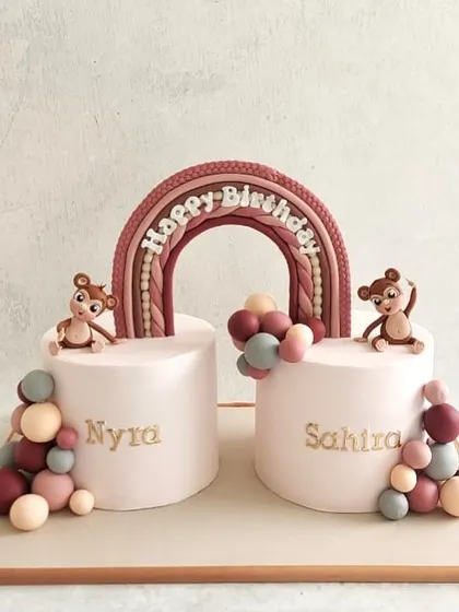 An adorable cake for twin girls, Nyra and Sahira. We made two separate cakes connected by a beautiful rainbow, with cute monkey figurines.