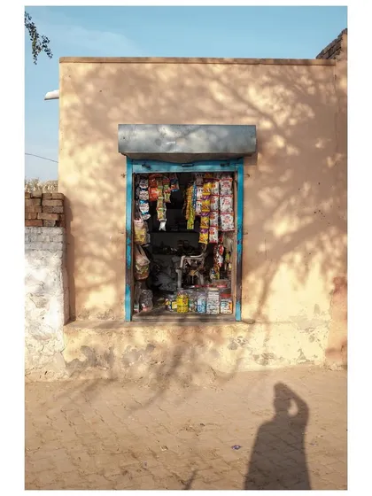 A small village shop in Rajasthan, its contents framed by the doorway, with my shadow visible in the foreground.