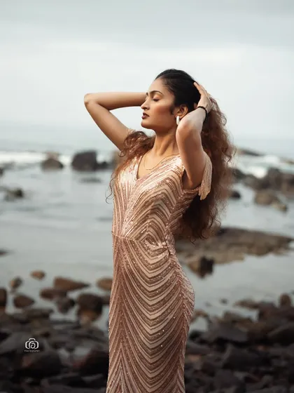 A beautiful portrait of a model in a shimmering gold gown on a rocky beach. The contrast between the glamorous dress and the rugged, natural setting creates a stunning and unexpected image.