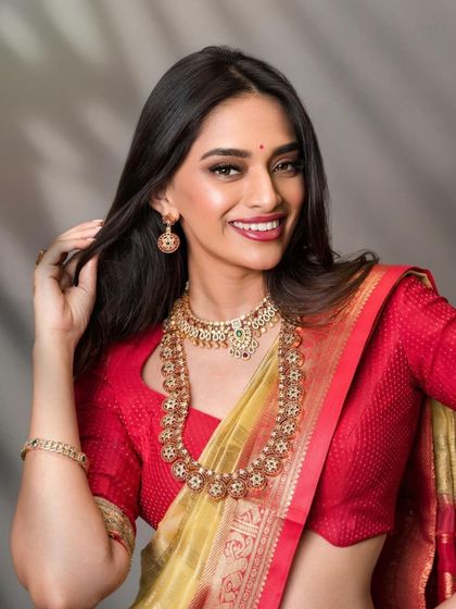 A classic South Indian bridal portrait with a focus on the jewelry and makeup. The lighting is carefully controlled to bring out the warm tones of the silk saree and the sparkle of the gold.