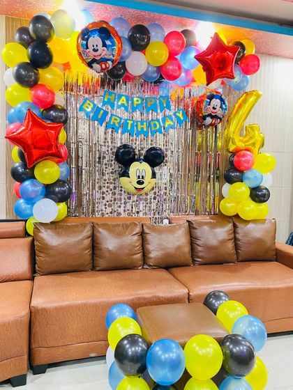 A classic Mickey Mouse theme for a 4th birthday party at home. The setup includes character foil balloons and a colorful balloon backdrop.
