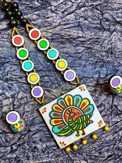 A vibrant terracotta peacock necklace set, perfect for pairing with a Paithani silk saree. The design is created using wooden blocks for printing on the clay, giving it a unique, rustic texture.