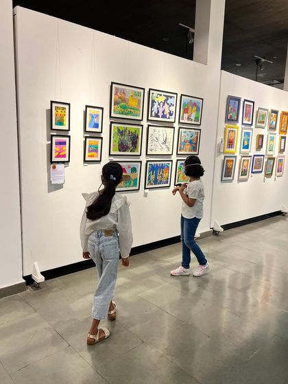 Two young visitors admiring the artworks at our annual student exhibition, "Through the Eyes of a Child."