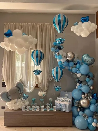 A classic "Welcome home baby boy" setup. The room is filled with blue and silver balloons, hot air balloon foils, and an adorable elephant balloon sculpture.